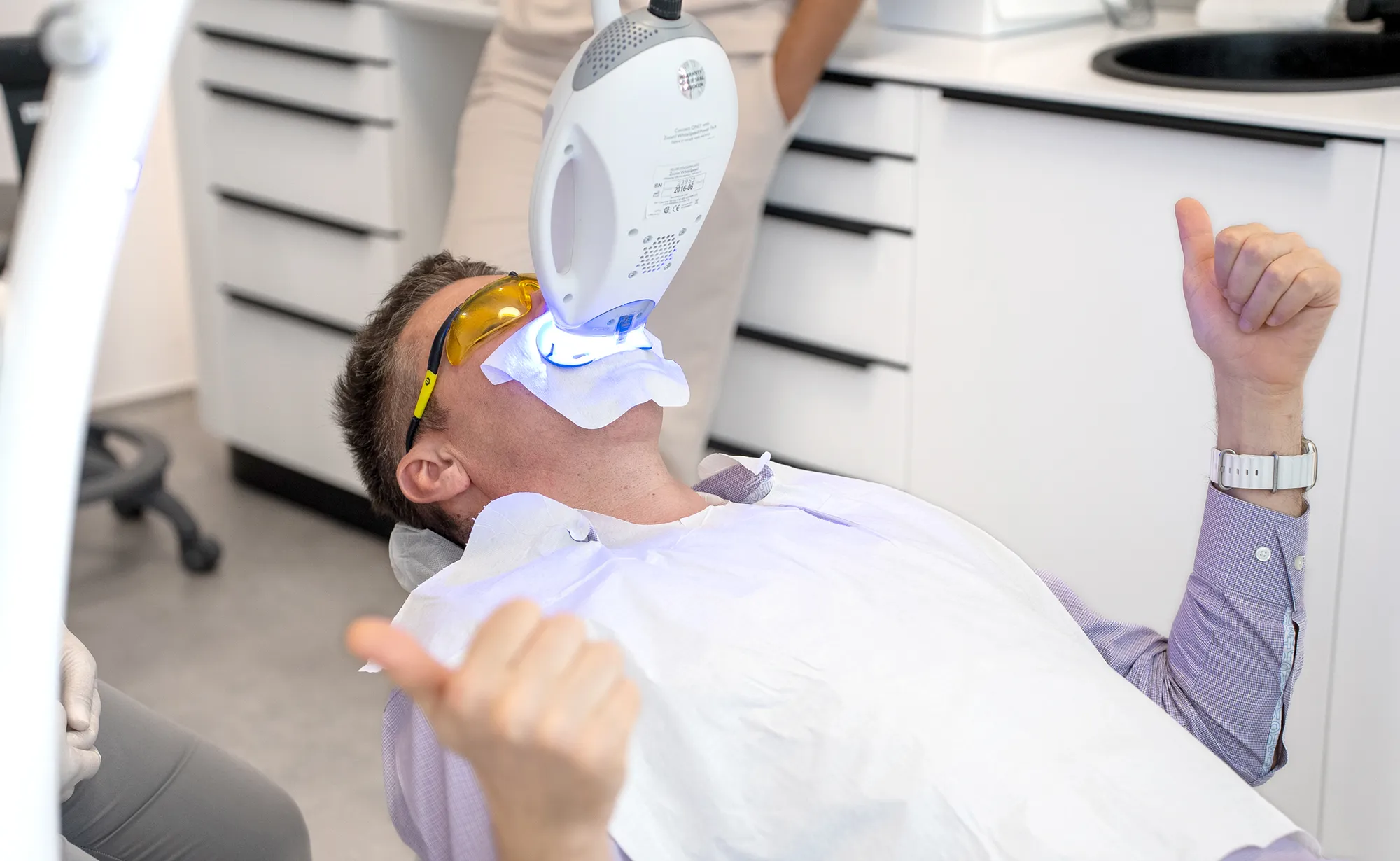 Patient during in-clinic whitening, giving a thumbs up